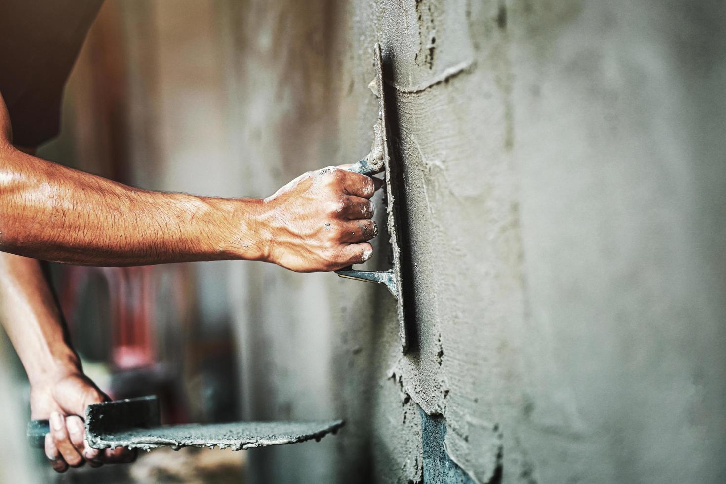 closeup hand of worker plastering cement at wall for building house photo