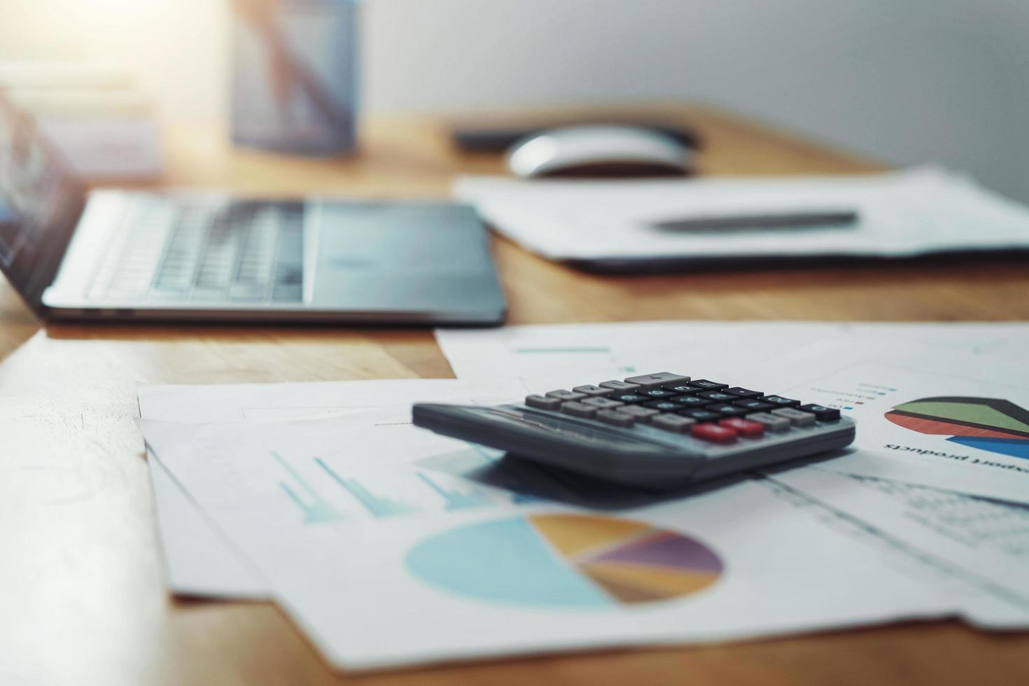 calculator with paperwork and laptop on desk in office. concept finance and accounting photo