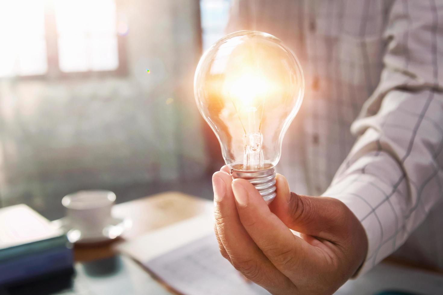 businessman hand holding light bulb in office. concept save energy power photo