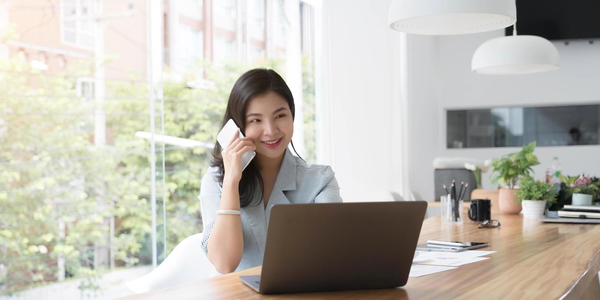 Asian business woman have the joy of talking on the phone, laptop and tablet on the office desk. photo