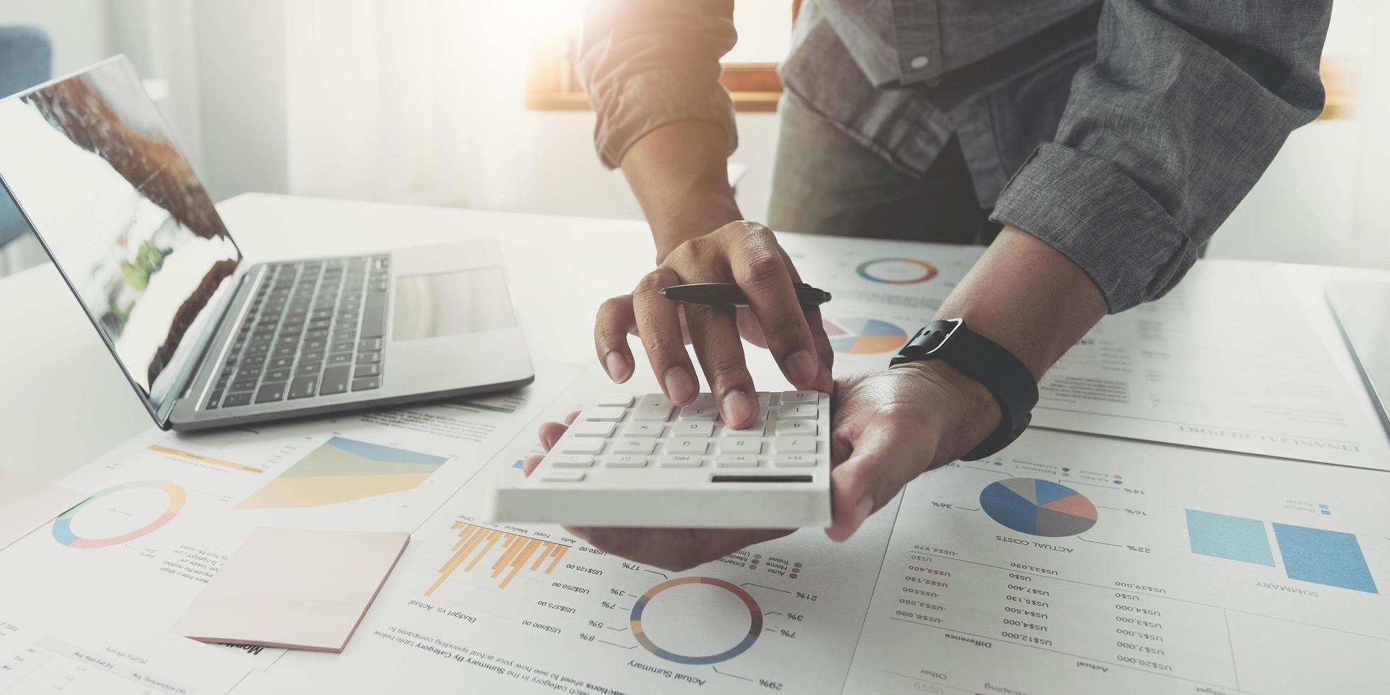 Close up businessman hand using calculator and working with laptop calculate about finance accounting at coffeeshop outdor.finance accounting concept photo