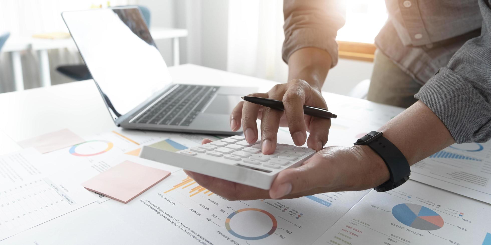 Close up businessman hand using calculator and working with laptop calculate about finance accounting at coffeeshop outdor.finance accounting concept photo