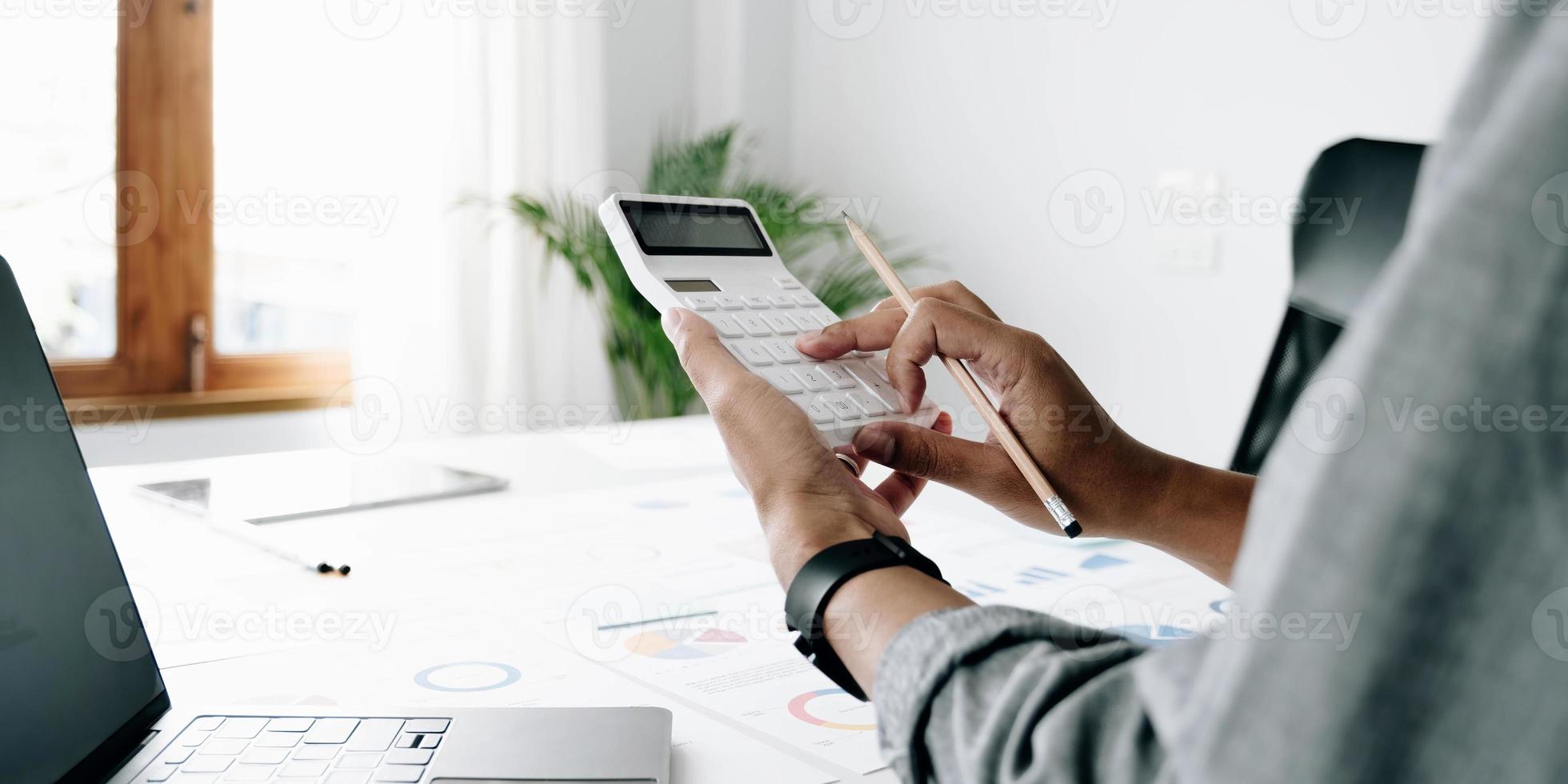 Close up businessman hand using calculator and working with laptop calculate about finance accounting at coffeeshop outdor.finance accounting concept photo