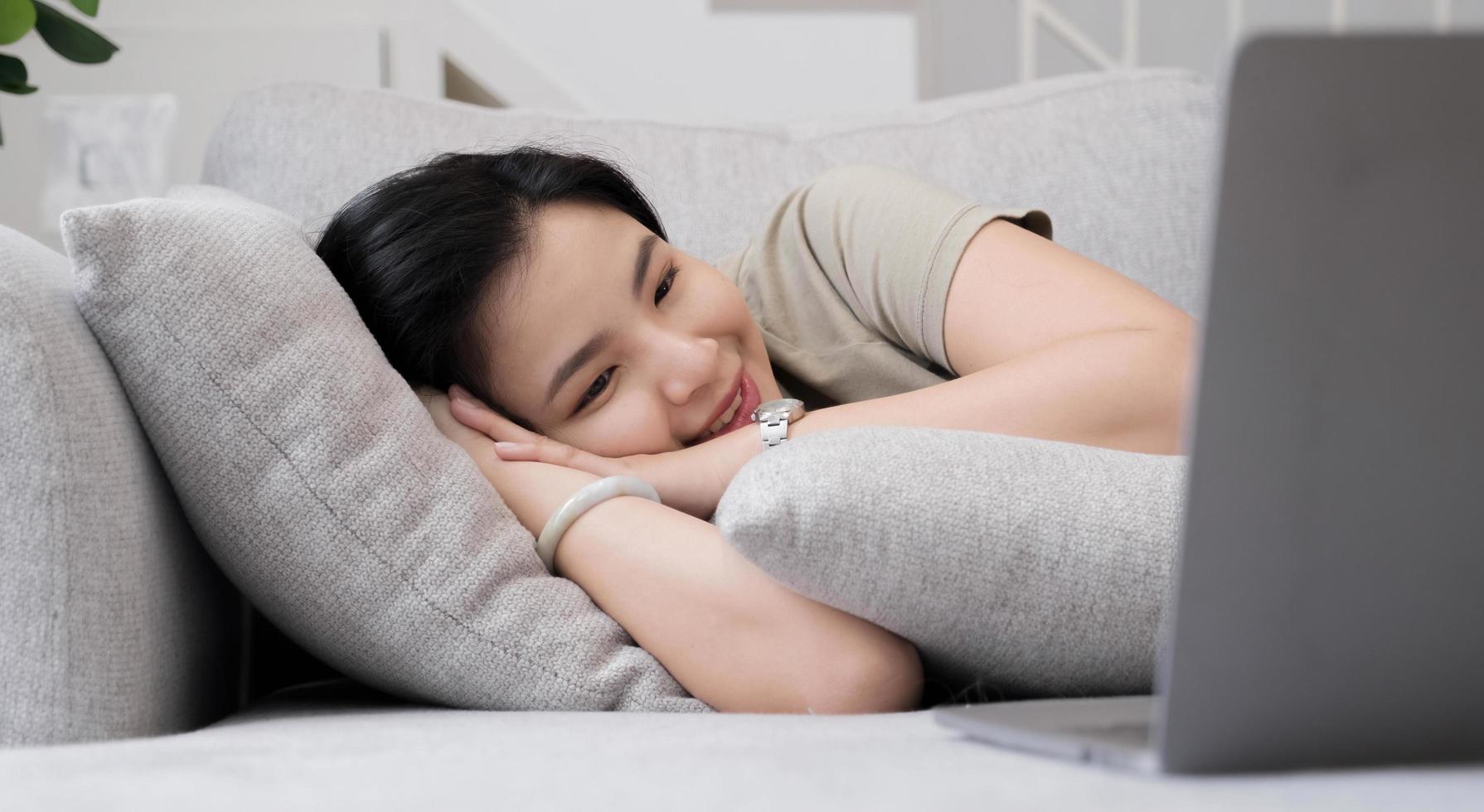 social media time stay in touch with her tablet A cheerful woman lies on the sofa using a tablet at home in the living room. smiling woman with tablet on sofa photo