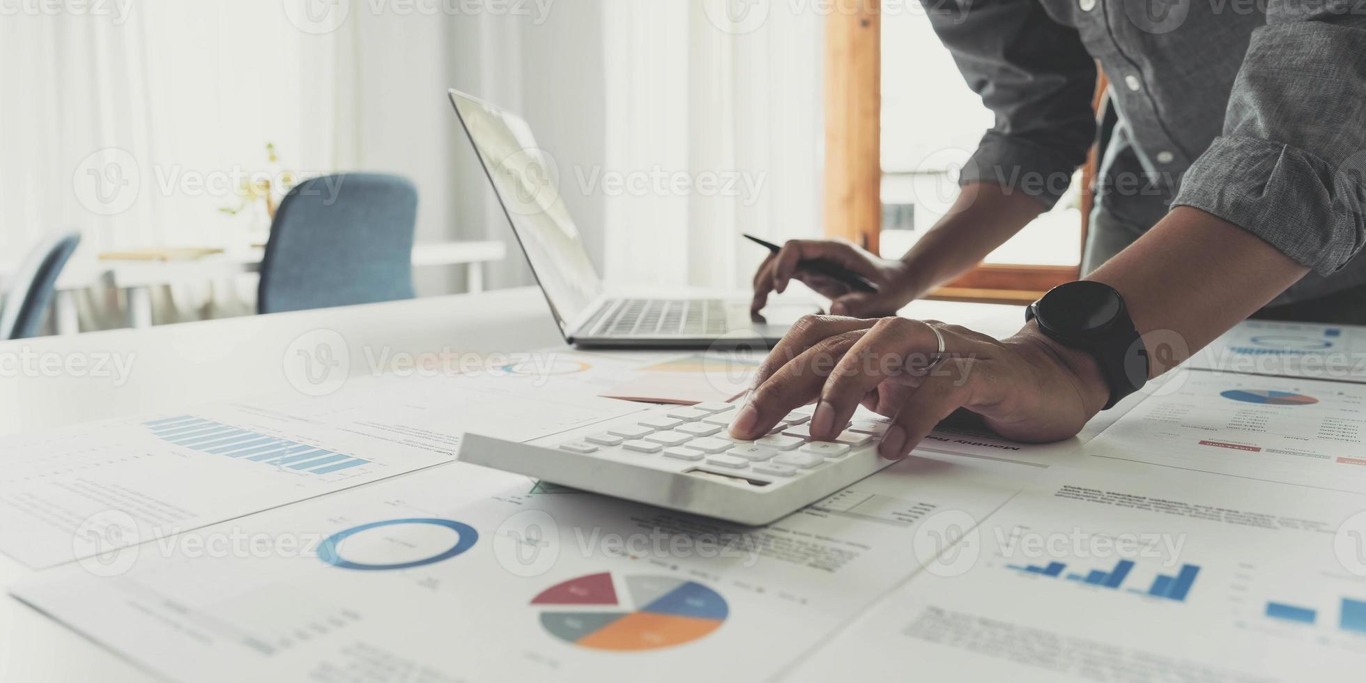 Business man working at office with digital tablet and laptop computer calculating financial report graph data documents on desk, close up, business analysis, work process concept photo
