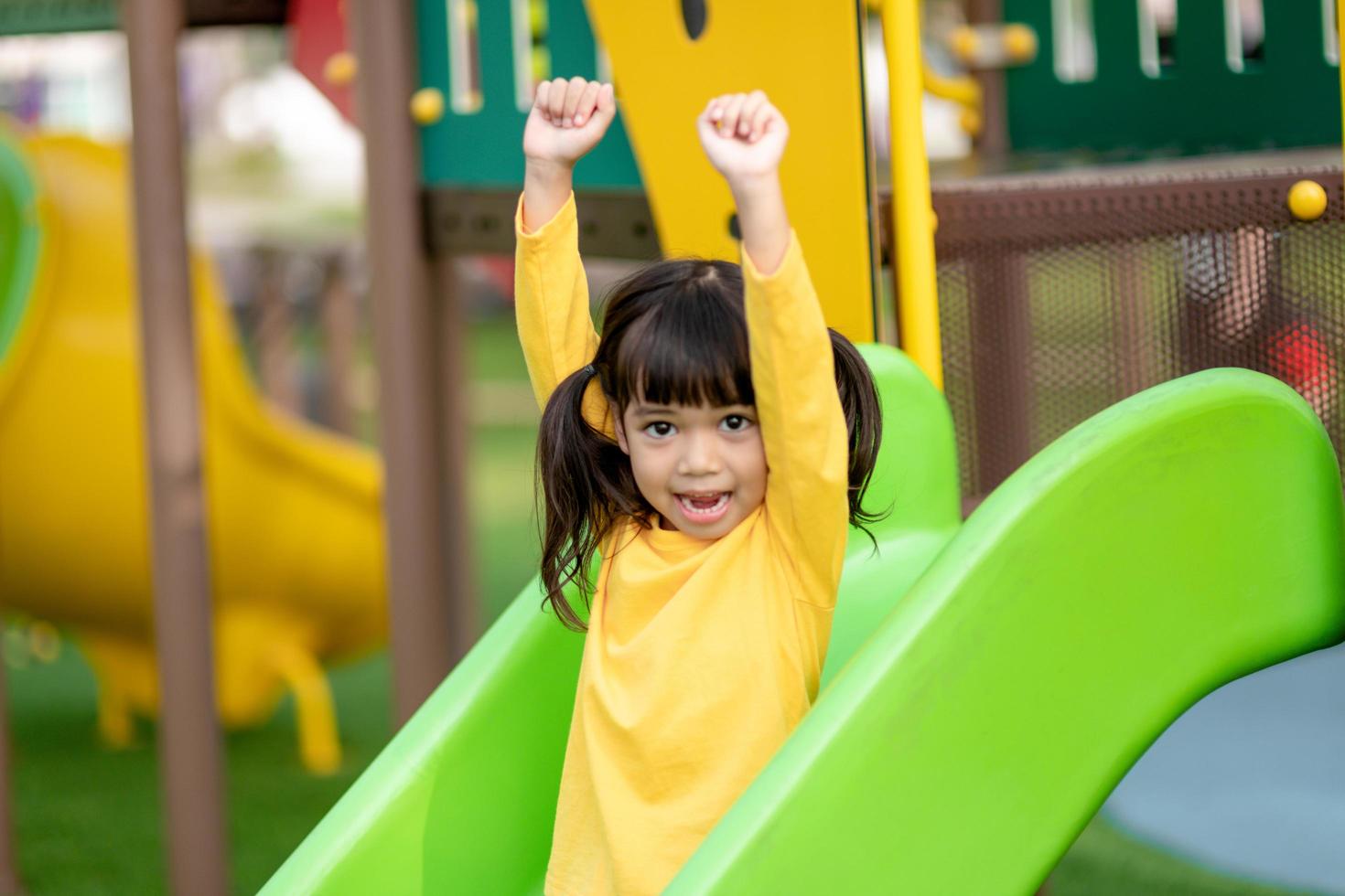 niña asiática disfruta jugando en un parque infantil, retrato al aire libre foto