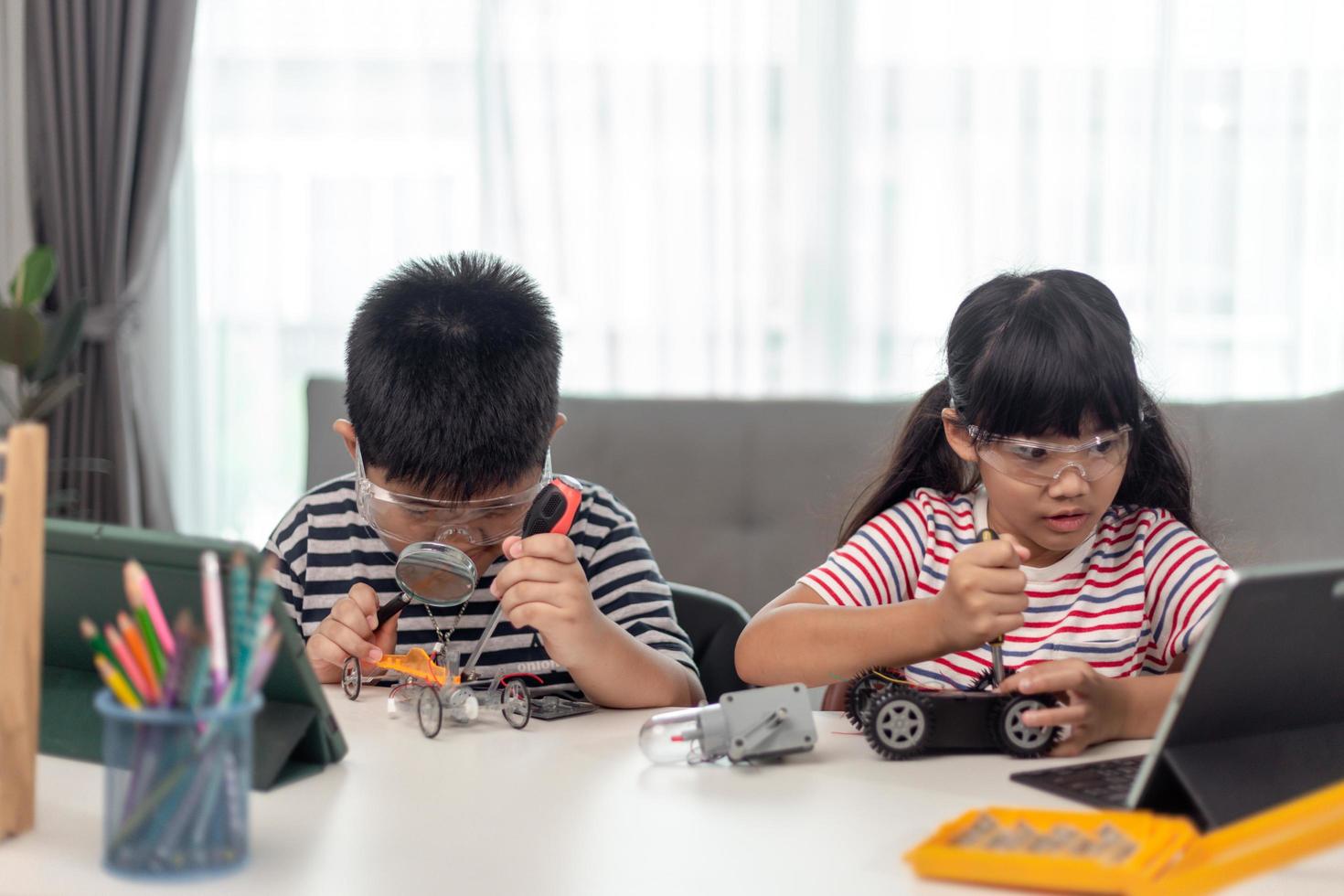 two Asian children having fun learning coding together, learning remotely at home, STEM science, homeschooling education, fun social distancing, isolation, new normal concept photo