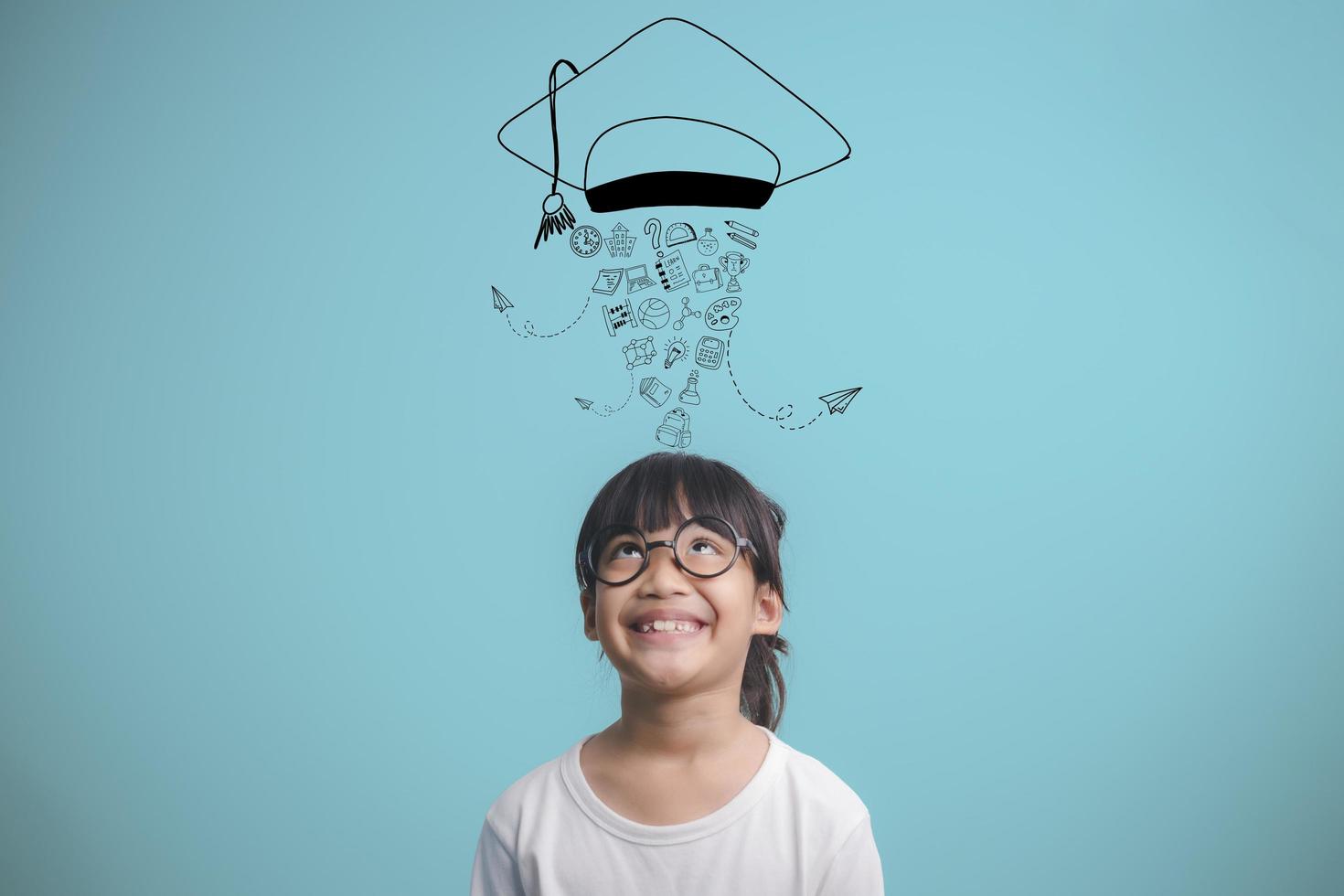 Happy Asian school kid graduate thinking with graduation cap photo