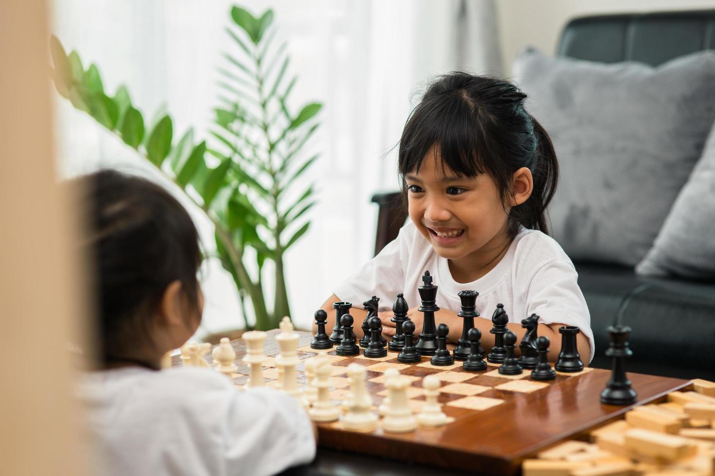 dos lindos niños jugando al ajedrez en casa foto