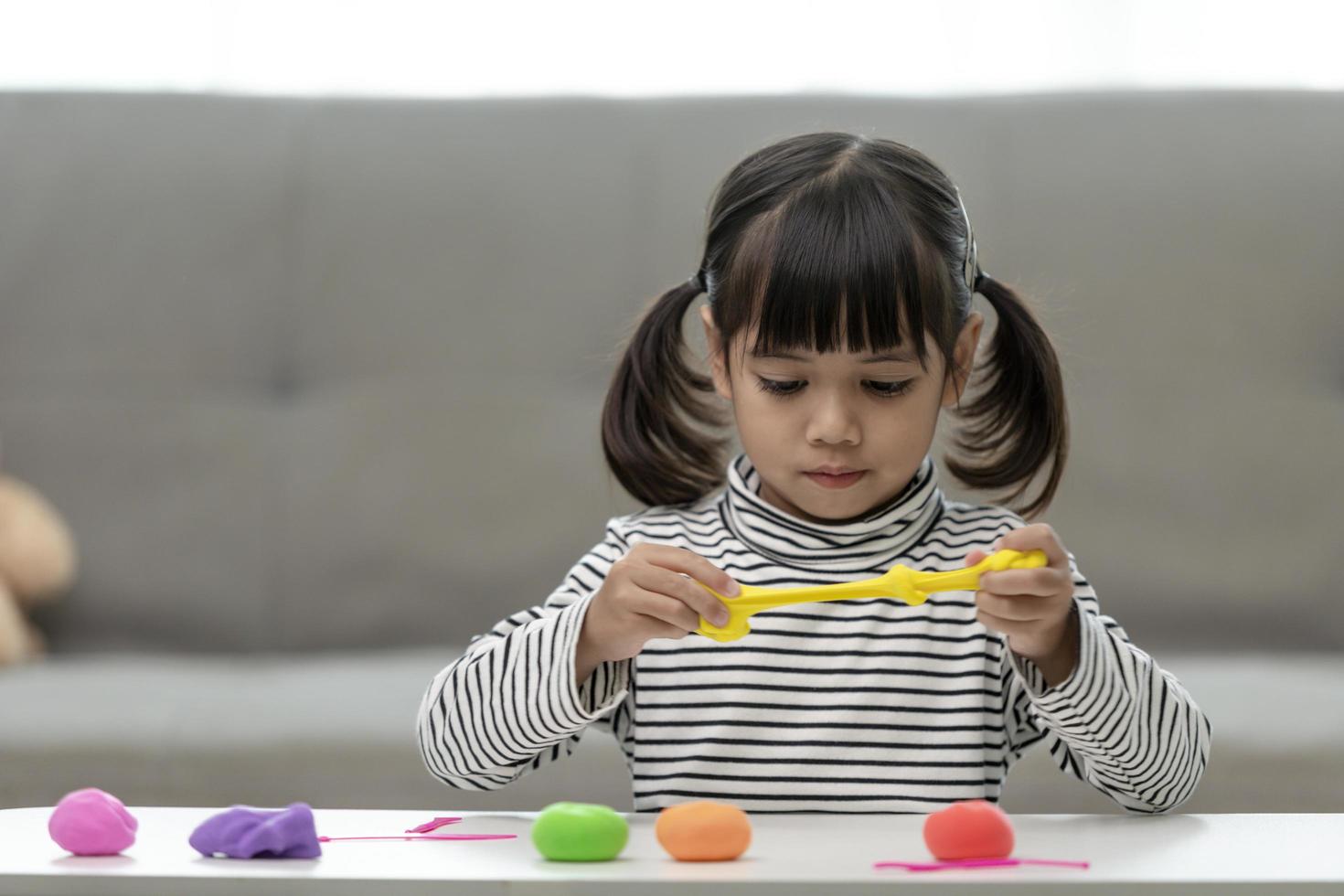 la niña está aprendiendo a usar plastilina de colores en una habitación bien iluminada foto