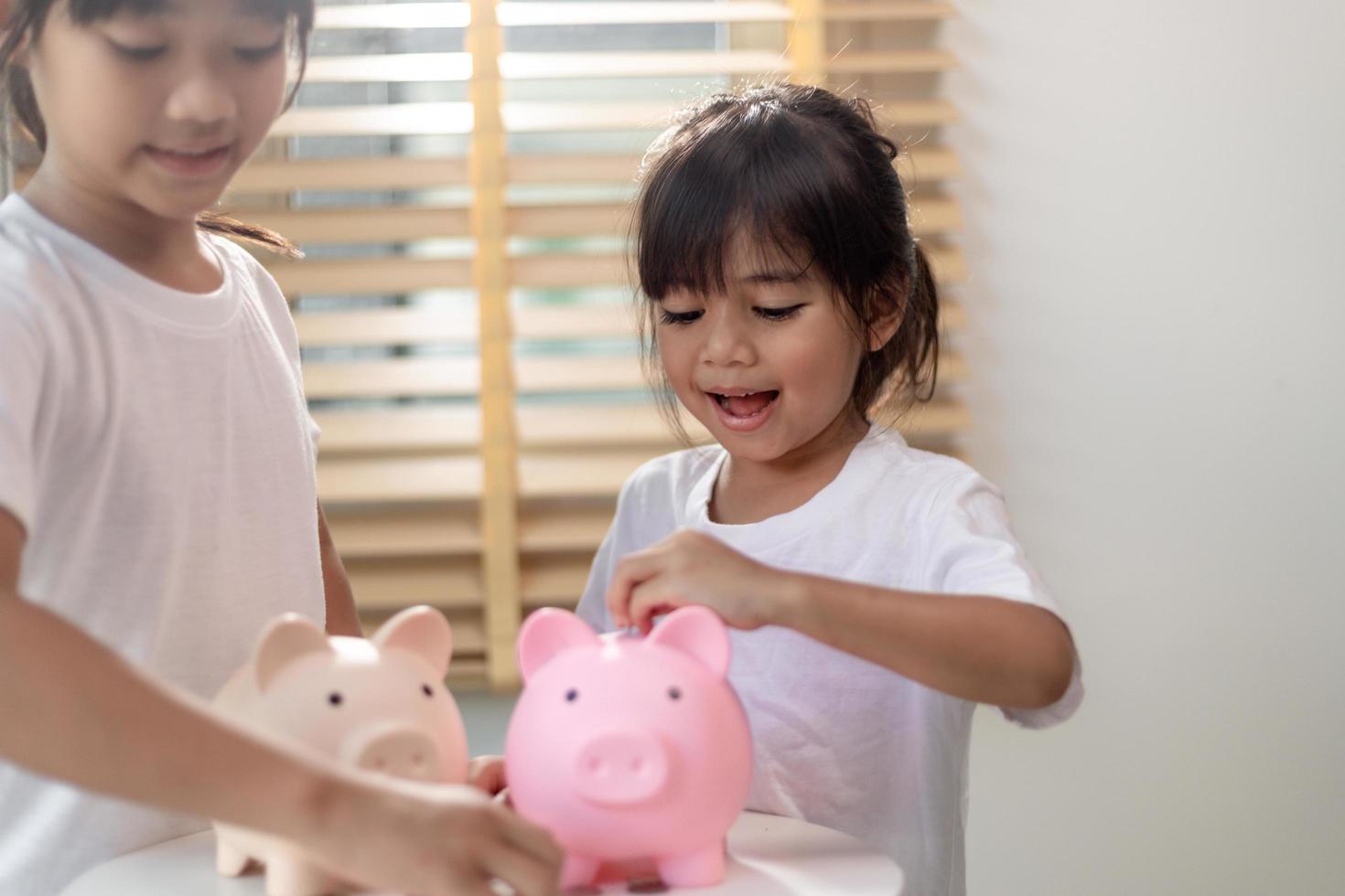 Little Asian girl saving money in a piggy bank, learning about saving, Kid save money for future education. Money, finances, insurance, and people concept photo