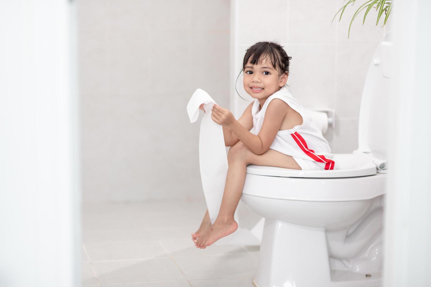 The little girl is sitting on the toilet suffering from constipation or hemorrhoid. photo