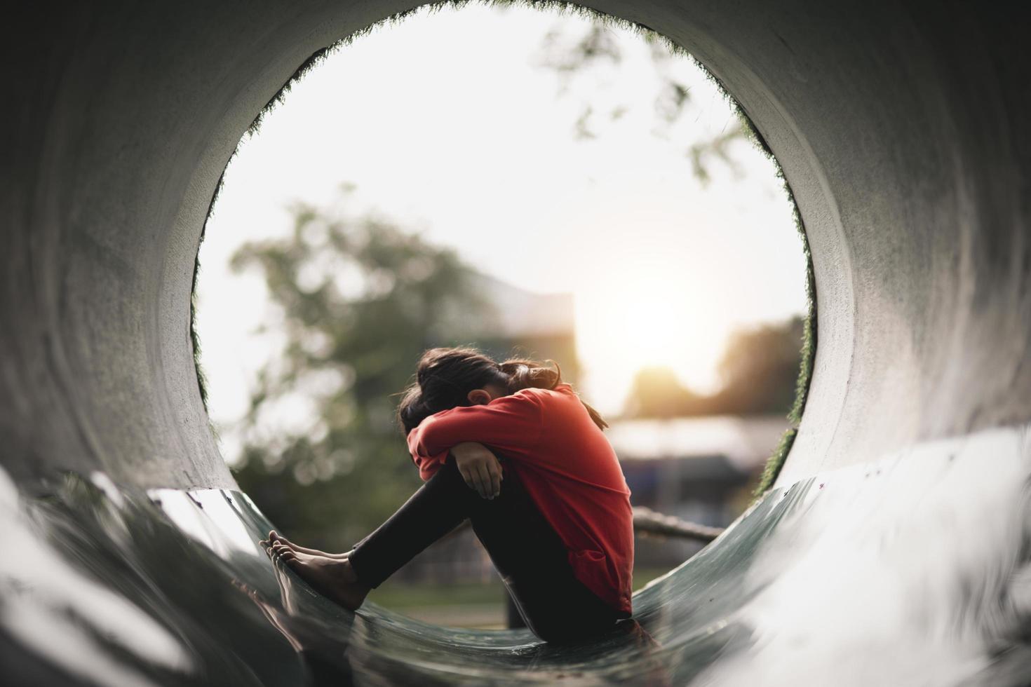 una chica asiática solitaria sentada sola en el parque, una chica tailandesa triste piensa algo, concepto de chica triste foto