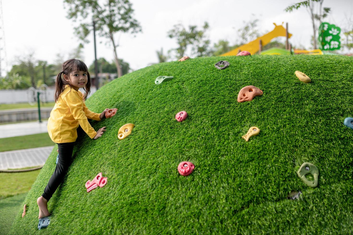 Child playing on outdoor playground. Kids play on school or kindergarten yard. Active kid on colorful slide and swing. Healthy summer activity for children. Little girl climbing outdoors. photo