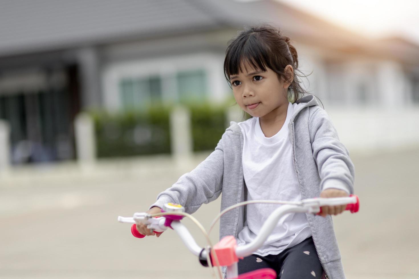 Children learning to drive a bicycle on a driveway outside. Little girls riding bikes on asphalt road in the city photo