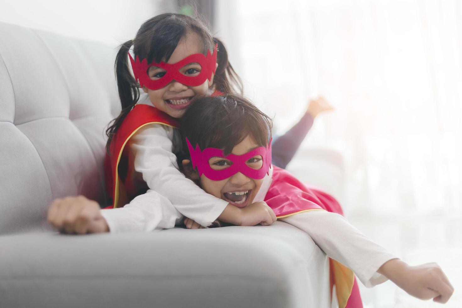 happy and confident young kids playing and dressing up as superhero together in bedroom photo
