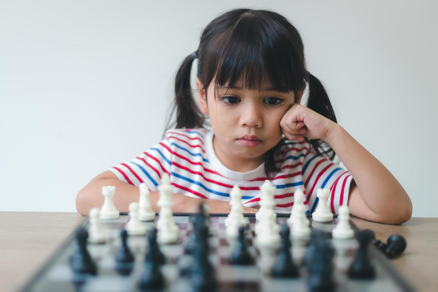 Asian little girl playing chess at home.a game of chess photo