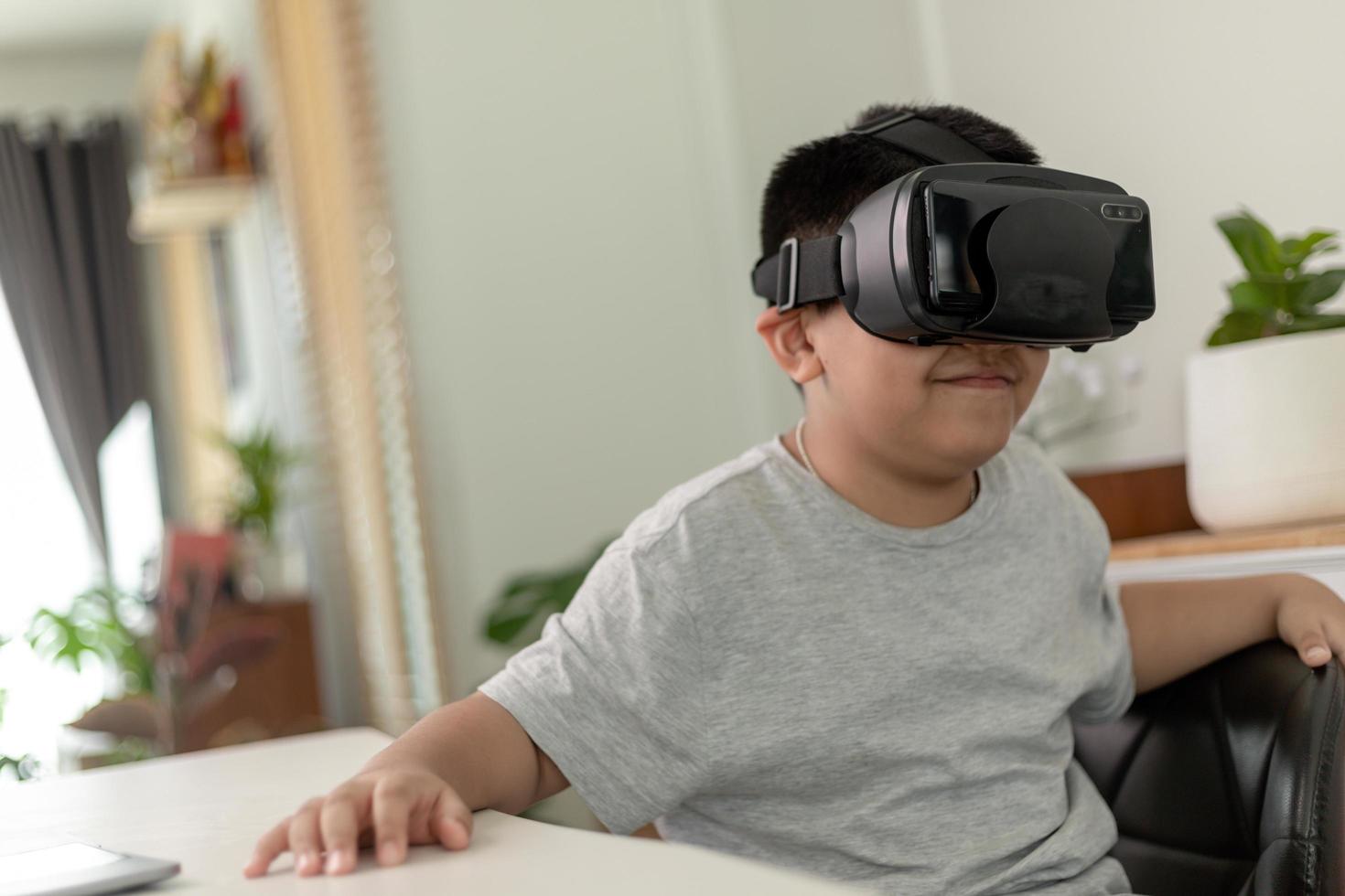 niño asiático con anteojos vr estudiando ciencias en casa, estudiante curioso usa un auricular de realidad virtual para estudiar ciencia en casa estudio en línea aprendizaje de estilo de vida futurista foto