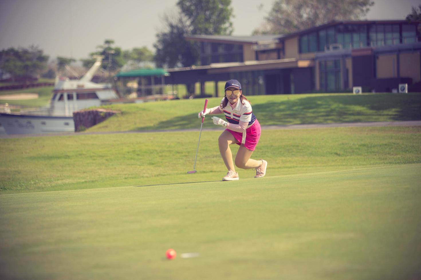 Golf player at the putting green hitting ball into a hole.Vintage color photo