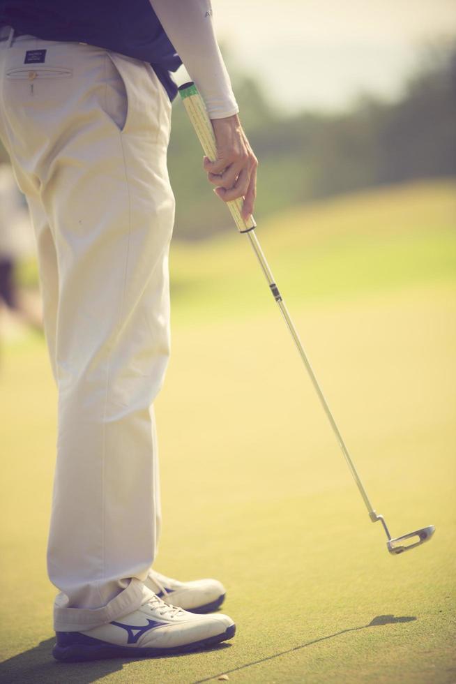 jugador de golf en el putting green golpeando la bola en un agujero.color vintage foto