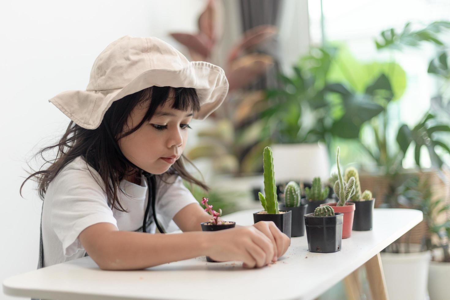 kid gently touch new stem of the cactus he grows with care, one hand holds magnifying glass.Nature education, Montessori and observation skills concept. photo