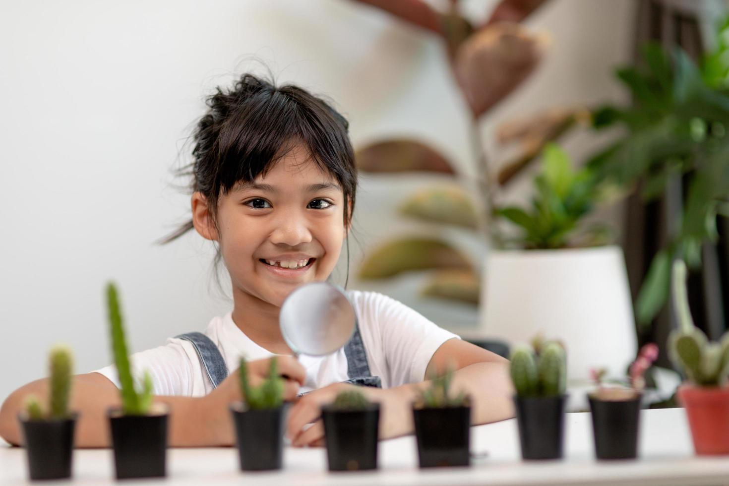 kid gently touch new stem of the cactus he grows with care, one hand holds magnifying glass.Nature education, Montessori and observation skills concept. photo