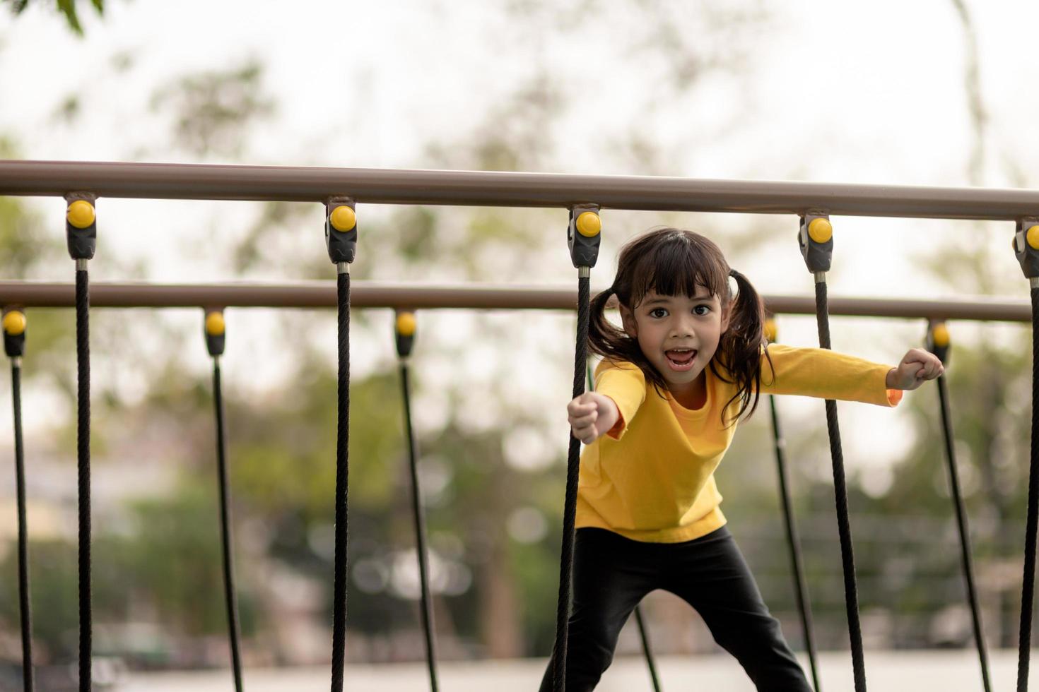 summer, childhood, leisure and people concept - happy little girl on children playground climbing frame photo