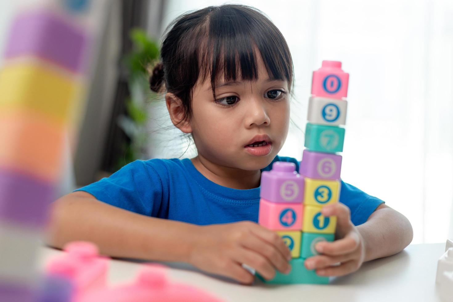 Adorable little girl playing toy blocks in a bright room photo