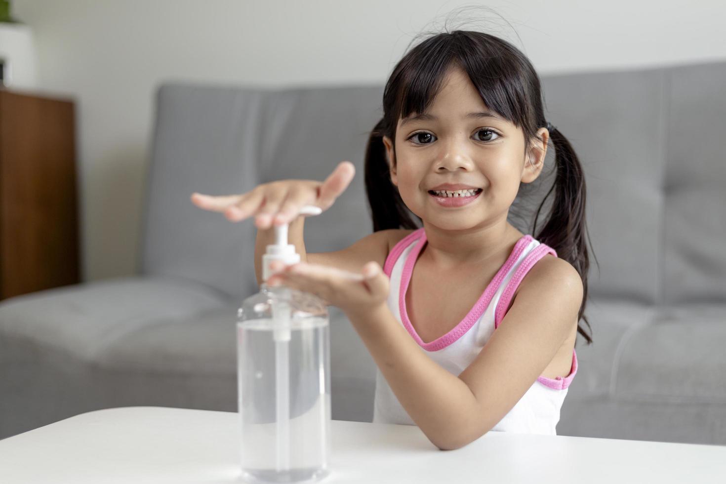 Little Asian girl child put alcohol gel sanitizer pump on Hands for cleaning or wash his hands. photo