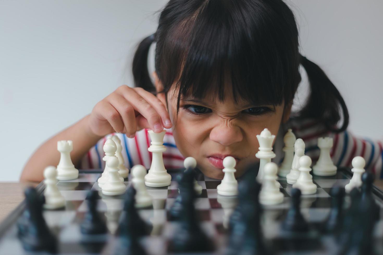 Asian little girl playing chess at home.a game of chess photo