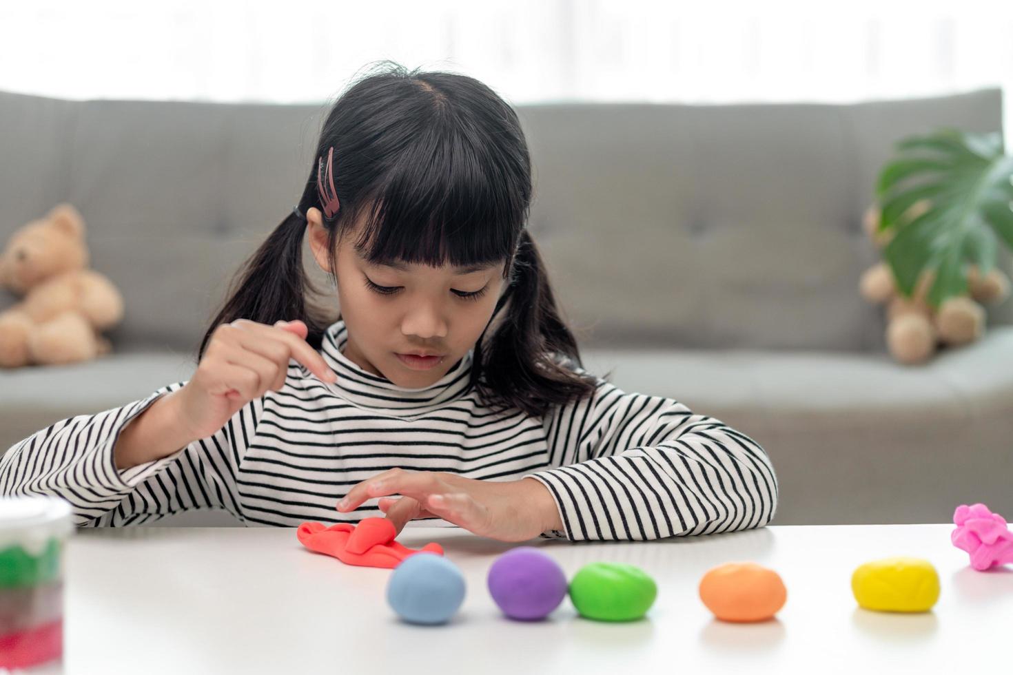 The little girl is learning to use colorful play dough in a well lit room photo