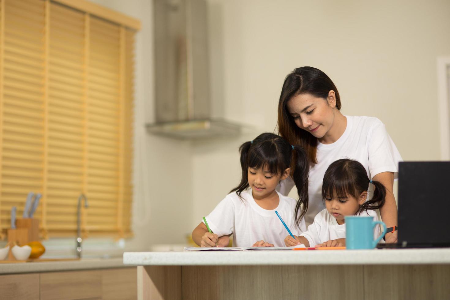 Happy mother and smiling daughter together painting using markers. Mother helping adopted child with art homework. Cheerful mother and asian little girl making painting at home. photo