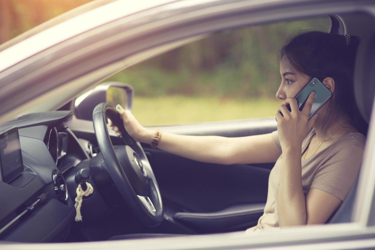 Young woman with telephone having phone conversation while driving car photo