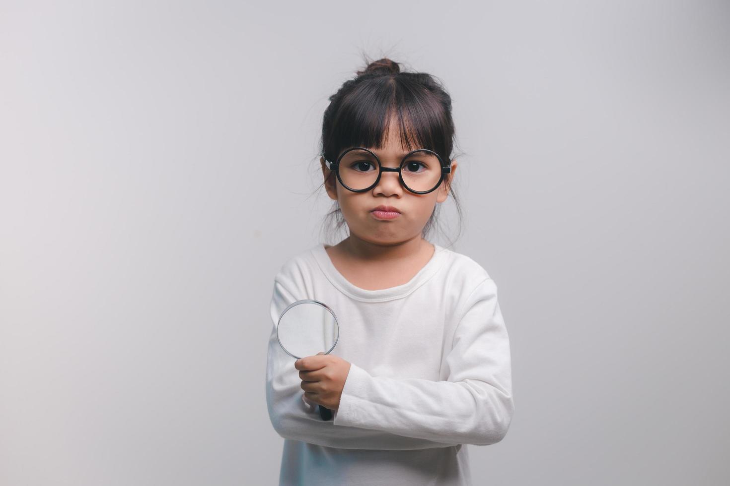 Little girl child holding a magnifying glass on white background photo