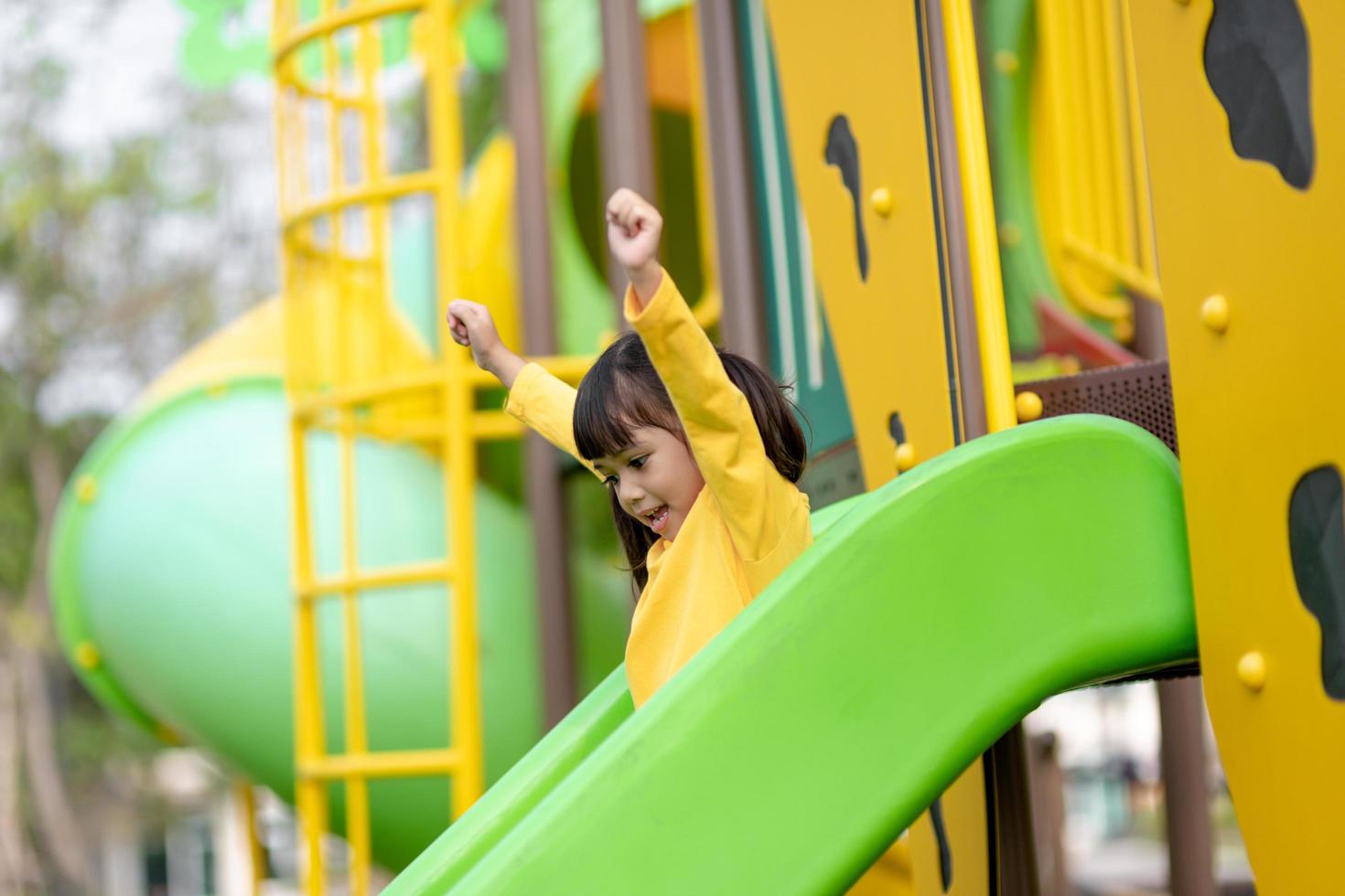 Child playing on outdoor playground. Kids play on school or kindergarten yard. Active kid on colorful slide and swing. Healthy summer activity for children. Little girl climbing outdoors. photo