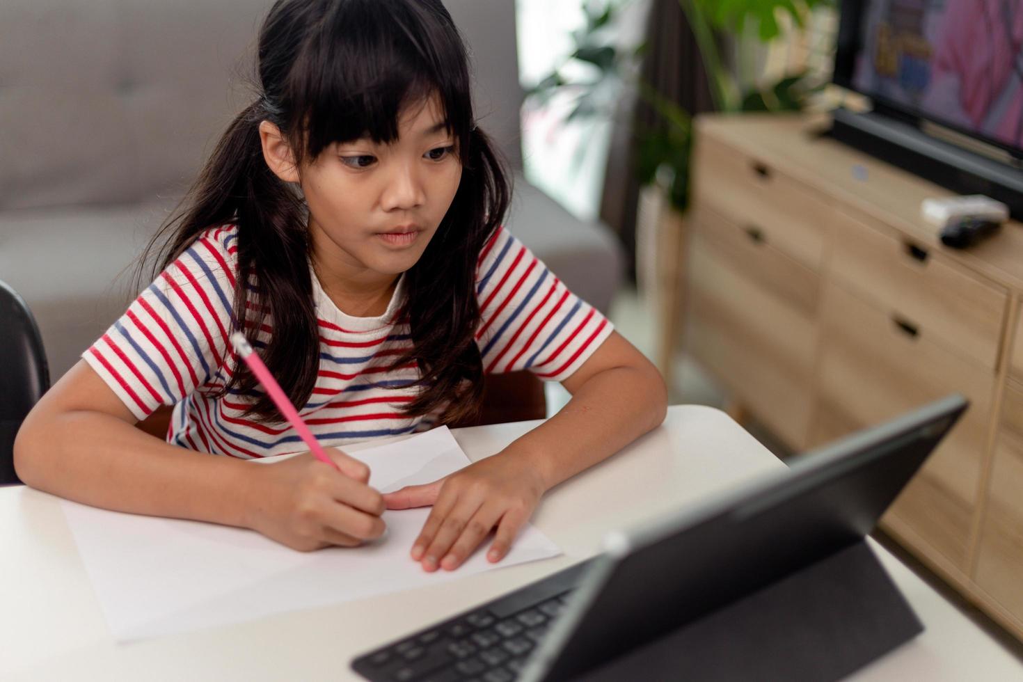 Cute Asian child learning class study online with video call from tablet at home .Social distancing concept photo