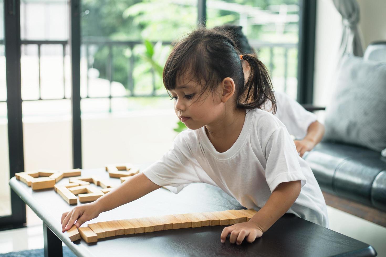 Two happy siblings playing a game with wooden blocks at home joyfully photo