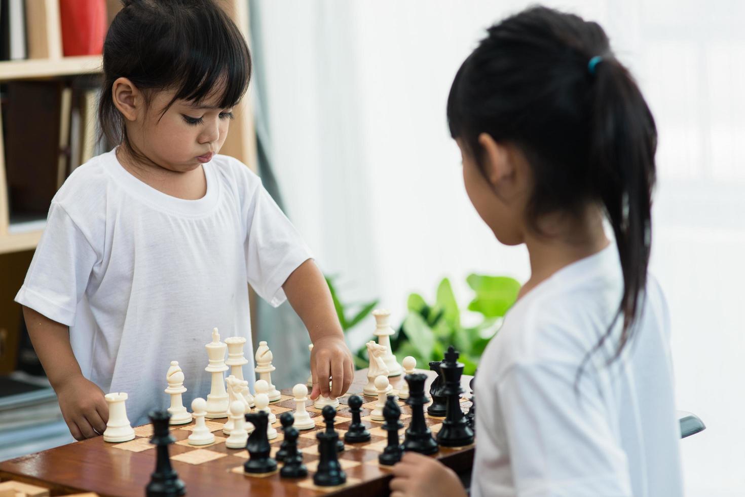 Two cute children playing chess at home photo