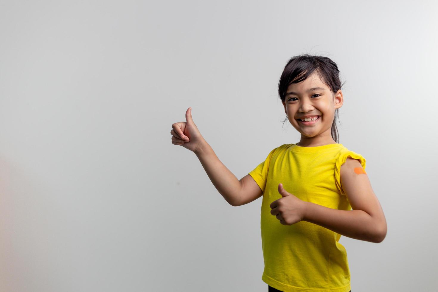 COVID 19 Vaccines for Kids concept. Studio a portrait of an adorable Asian girl after getting his first dose of vaccine. Immune, Safe, Available, Back to school. photo