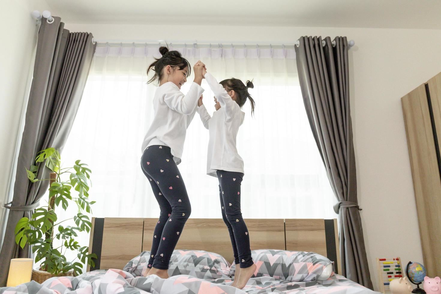 two little girls are jumping on the bed photo