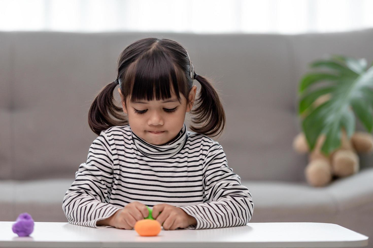 The little girl is learning to use colorful play dough in a well lit room photo