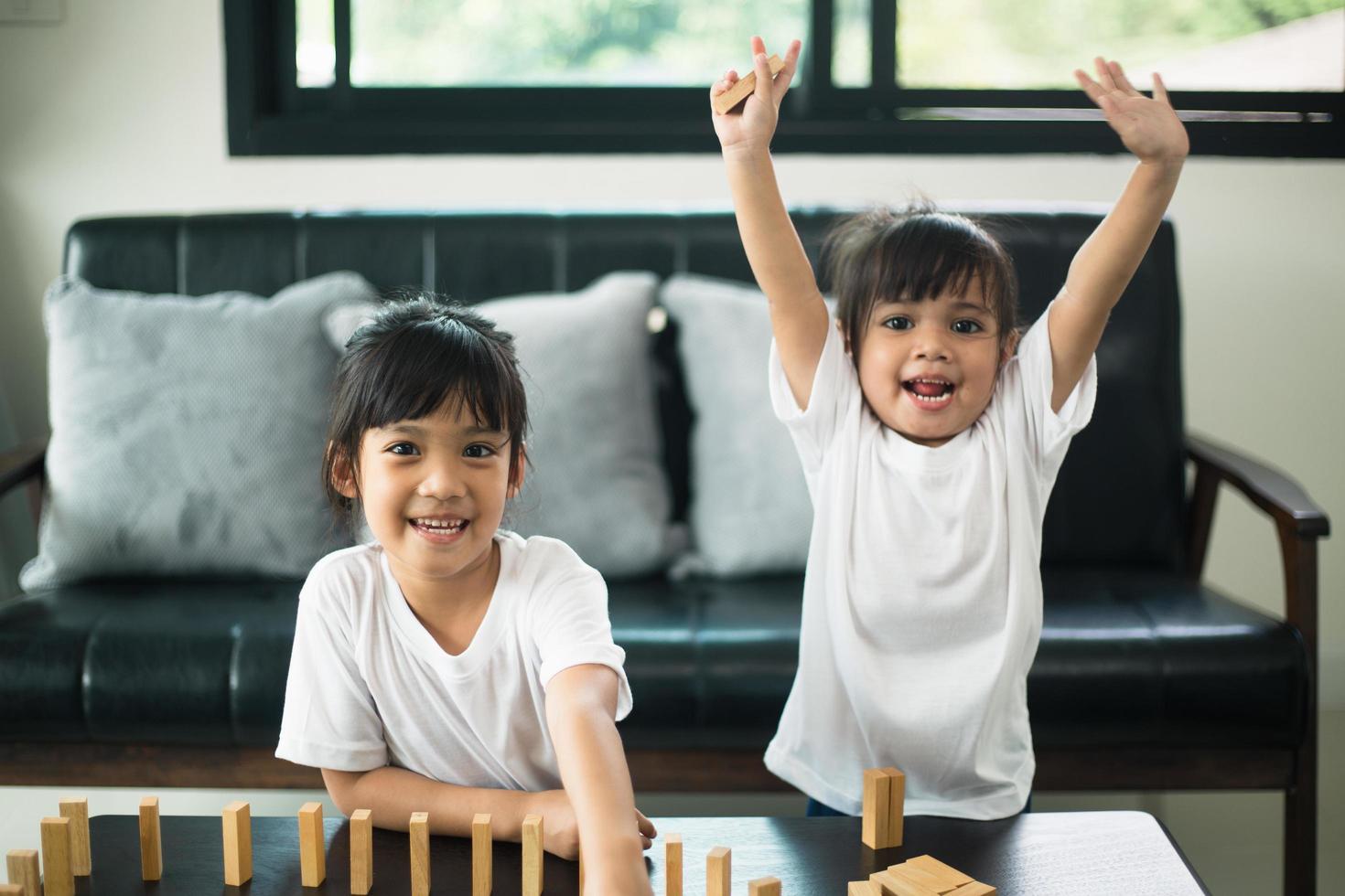 Two happy siblings playing a game with wooden blocks at home joyfully photo