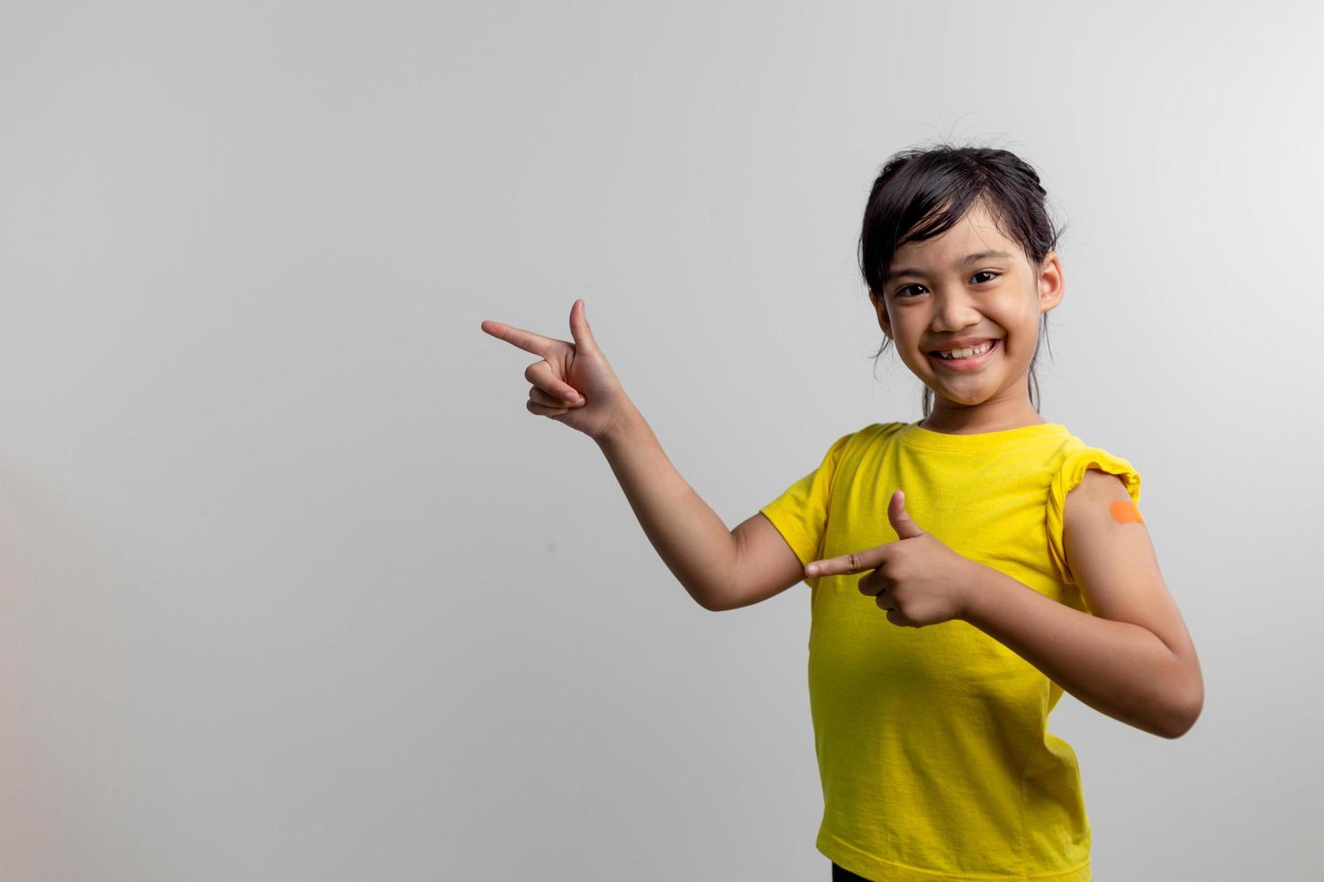 COVID 19 Vaccines for Kids concept. Studio a portrait of an adorable Asian girl after getting his first dose of vaccine. Immune, Safe, Available, Back to school. photo