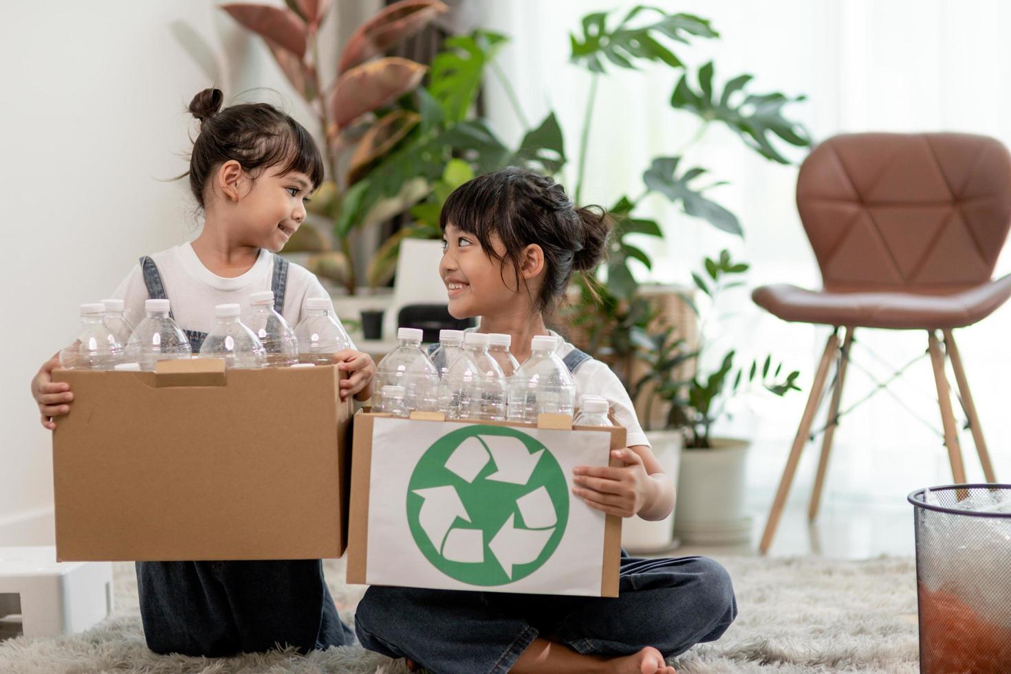 Smiling children having fun while segregating plastic bottles and paper into a bin photo