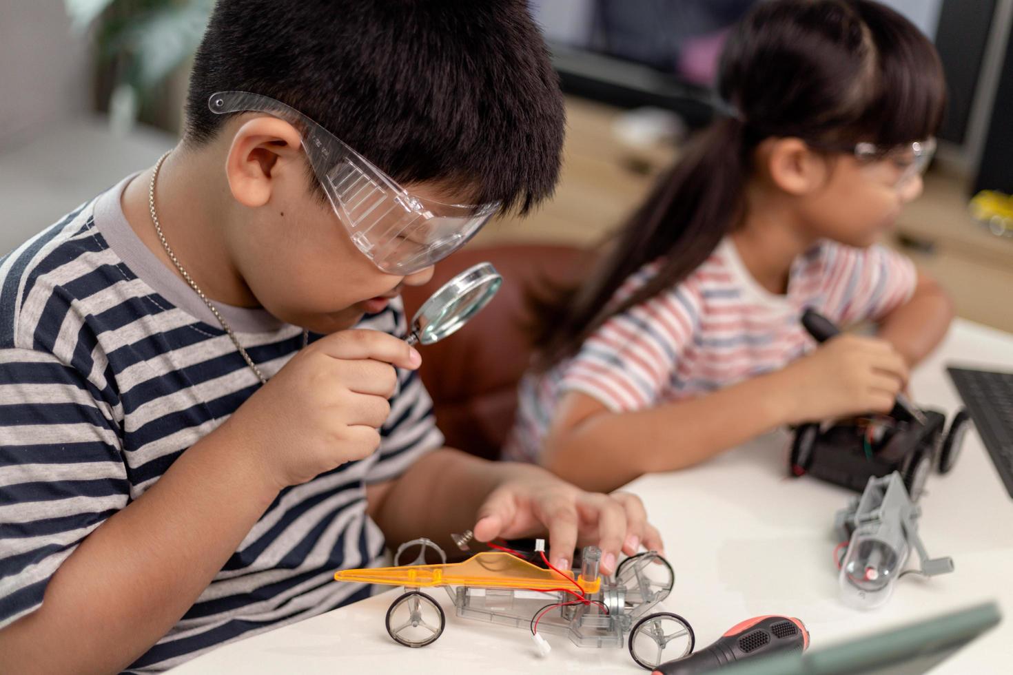 two Asian children having fun learning coding together, learning remotely at home, STEM science, homeschooling education, fun social distancing, isolation, new normal concept photo