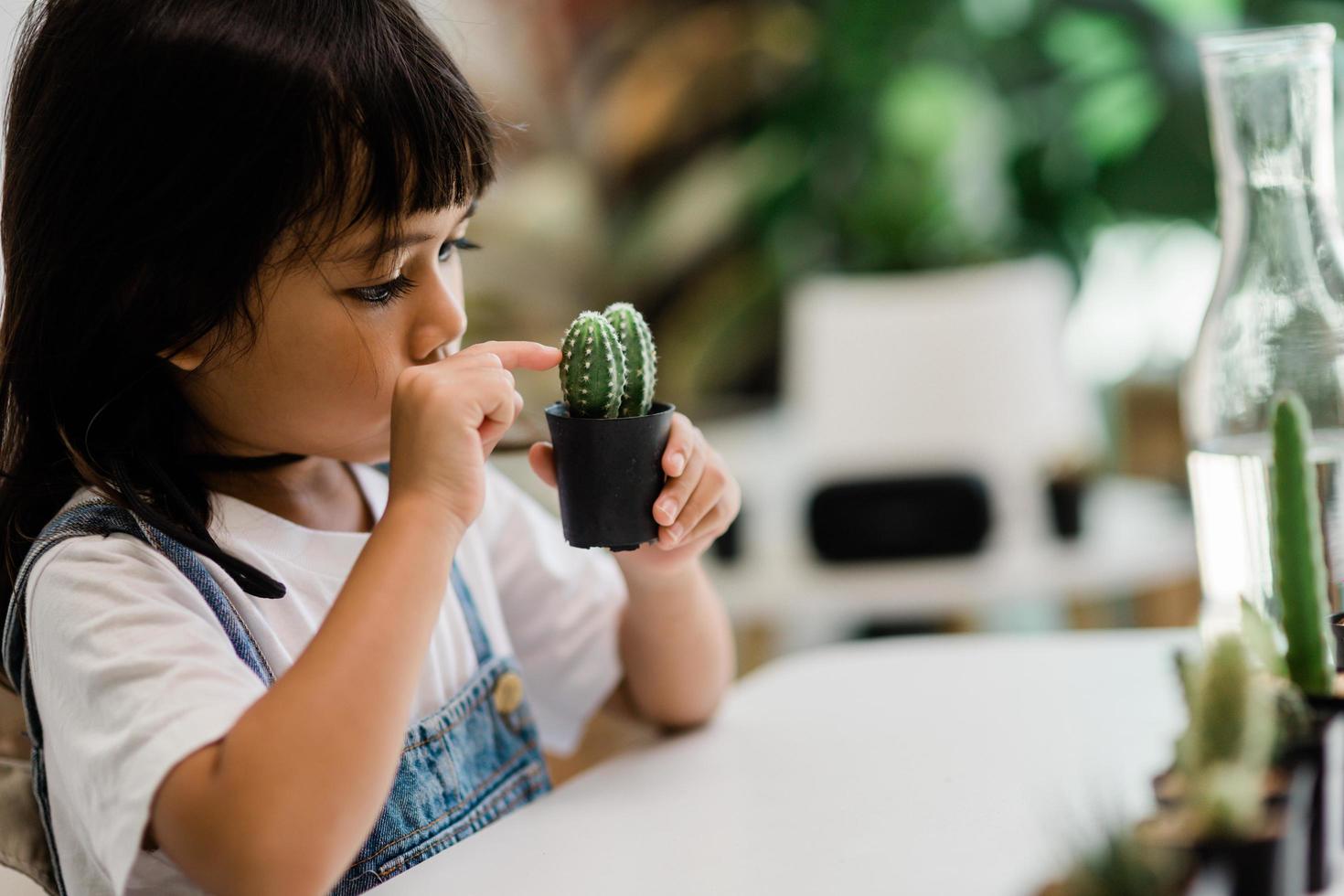 kid gently touch new stem of the cactus he grows with care, one hand holds magnifying glass.Nature education, Montessori and observation skills concept. photo