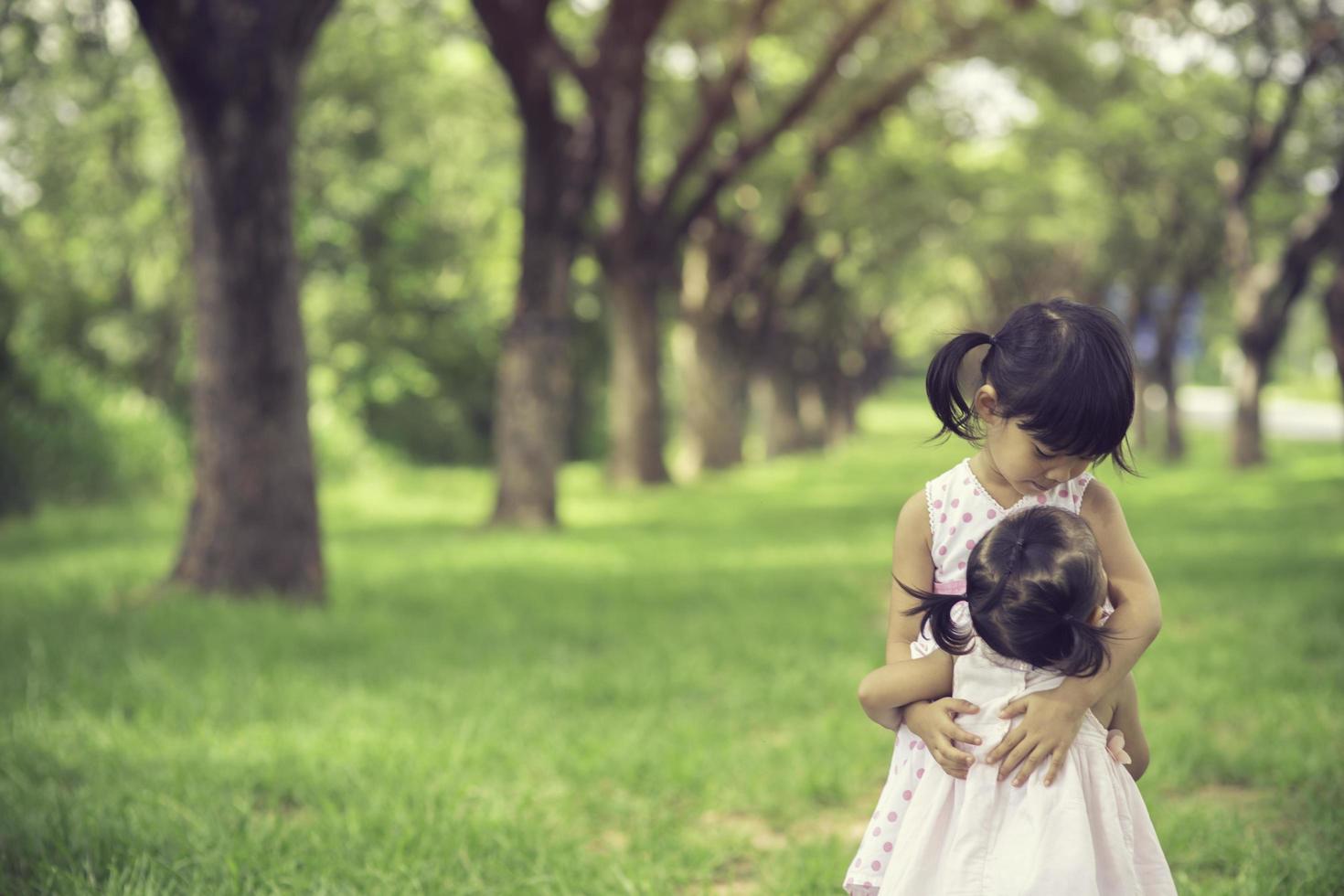 two little girl hugging in the forest photo