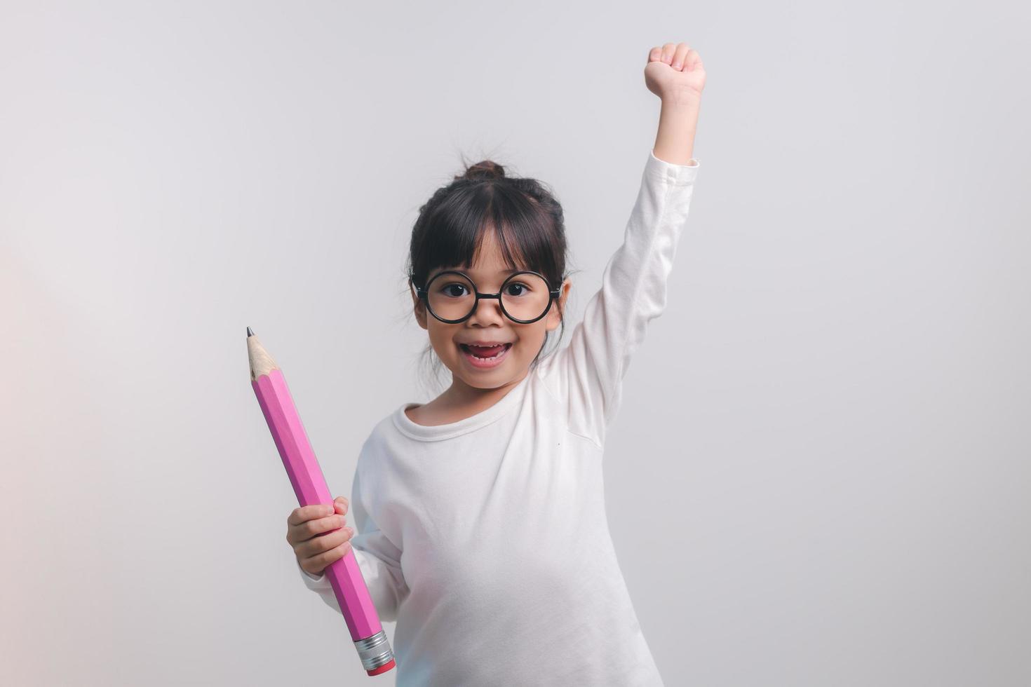 niña emocionada sosteniendo grandes lápices en sus manos. Regreso a la escuela. foto