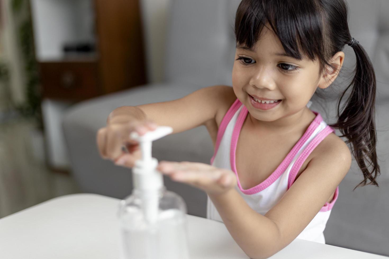 Little Asian girl child put alcohol gel sanitizer pump on Hands for cleaning or wash his hands. photo