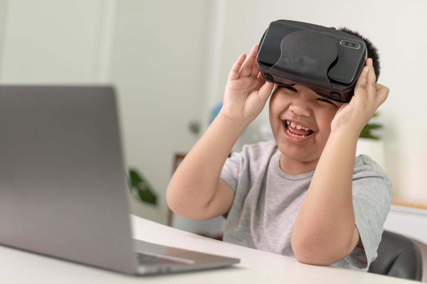 niño asiático con anteojos vr estudiando ciencias en casa, estudiante curioso usa un auricular de realidad virtual para estudiar ciencia en casa estudio en línea aprendizaje de estilo de vida futurista foto